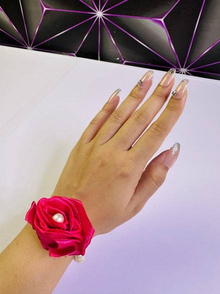 Hand wearing a pink wrist corsage with a decorative background