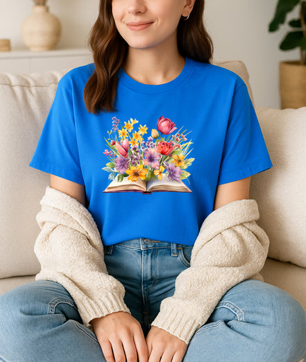 Women wearing a blue t-shirt with a floral book design, sitting on a couch.