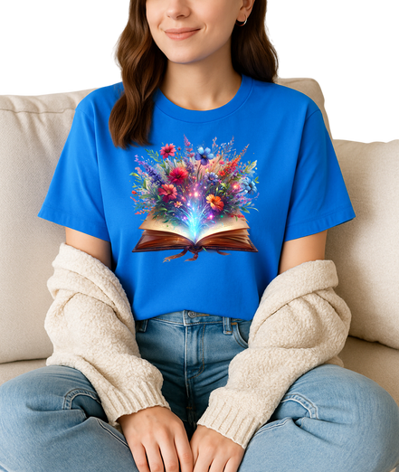 Person wearing a blue t-shirt with a colorful floral design on a book, sitting on a beige couch.