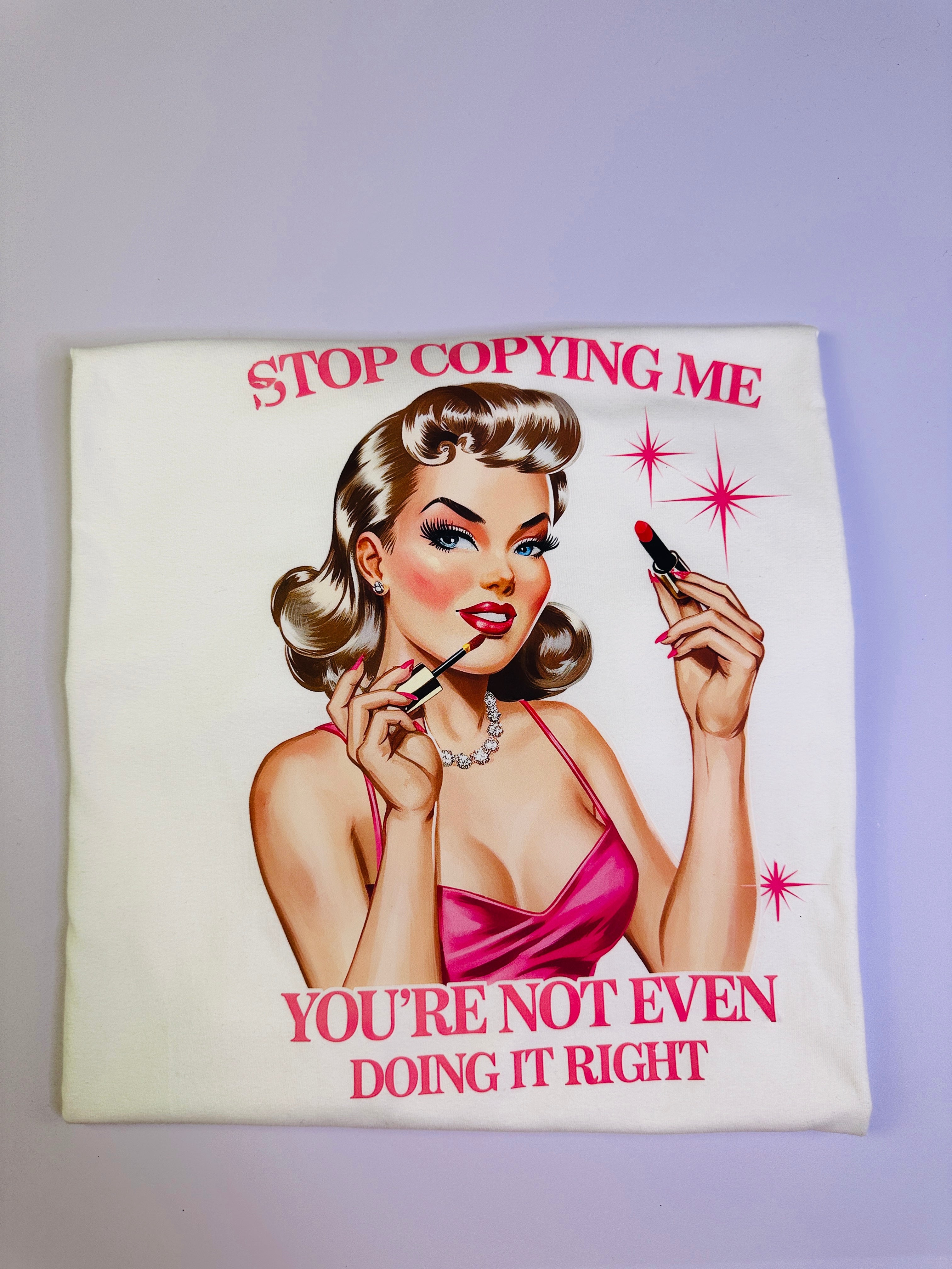 Vintage-style poster with a woman applying makeup and text 'Stop Copying Me, You're Not Even Doing It Right' on a light background.