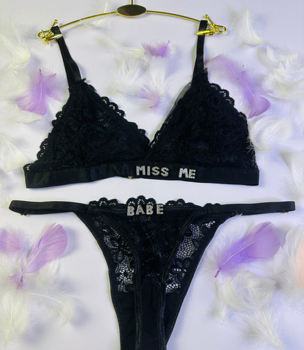 Black lace lingerie set with 'Miss Me' and 'Babe' text on a white background with purple flowers.