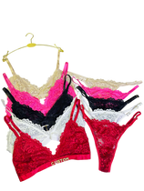 Set of colorful lace lingerie on hangers against a white background