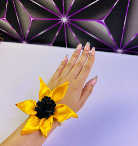 Hand wearing a yellow flower corsage Bracelet with a geometric background