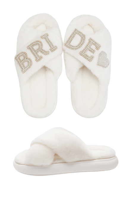 Pair of white slippers with 'Bride' and heart designs on a white background