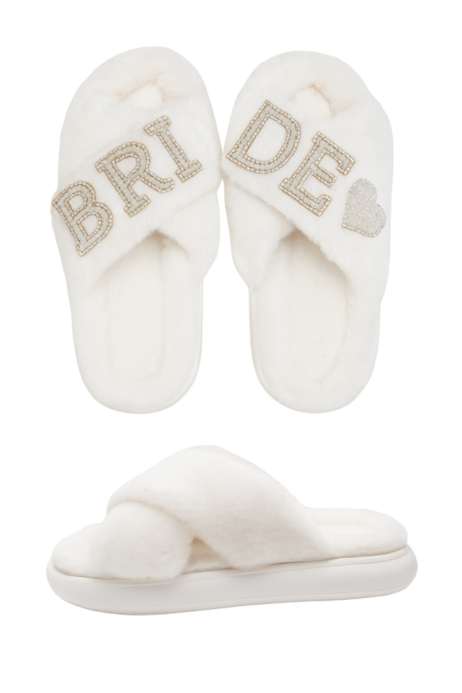 Pair of white slippers with 'Bride' and heart designs on a white background
